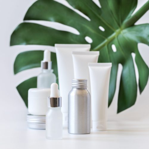 Cosmetics packaging with green herbal leaves.Set Different of cosmetic bottles of cream or lotion on white background.Blank packaging.Natural beauty spa product concept.Mock-up.